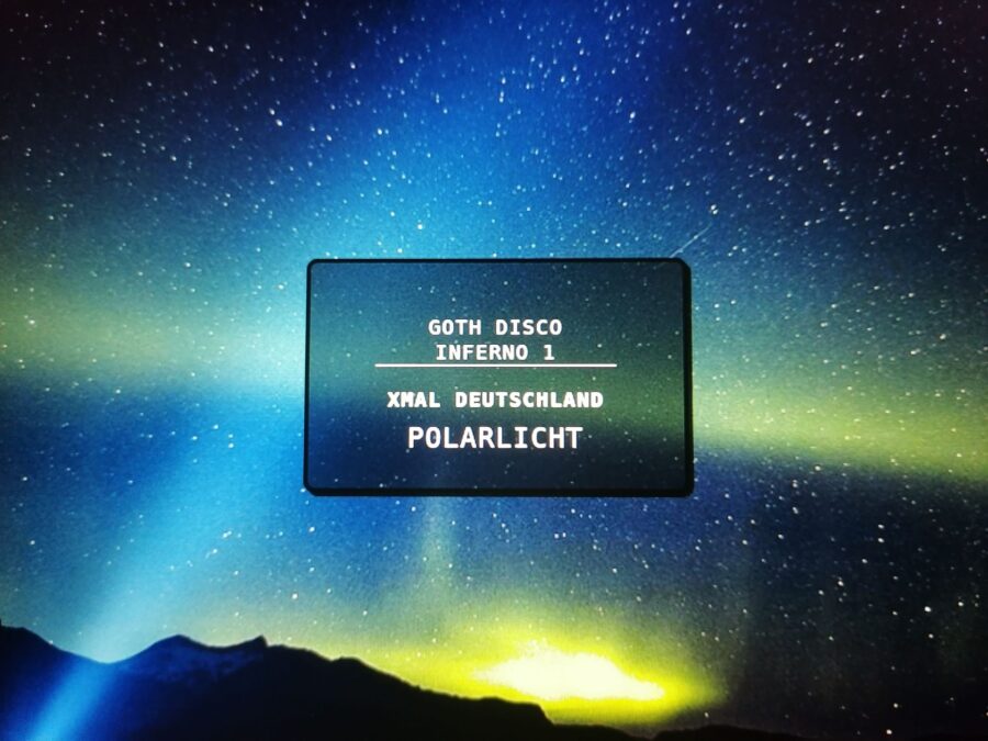 Foto einer Aurora Borealis, in der Mitte ist eine halbtransparente Tafel mit dem Text: "Goth Disco Inferno 1, Xmal Deutschland - Polarlicht".