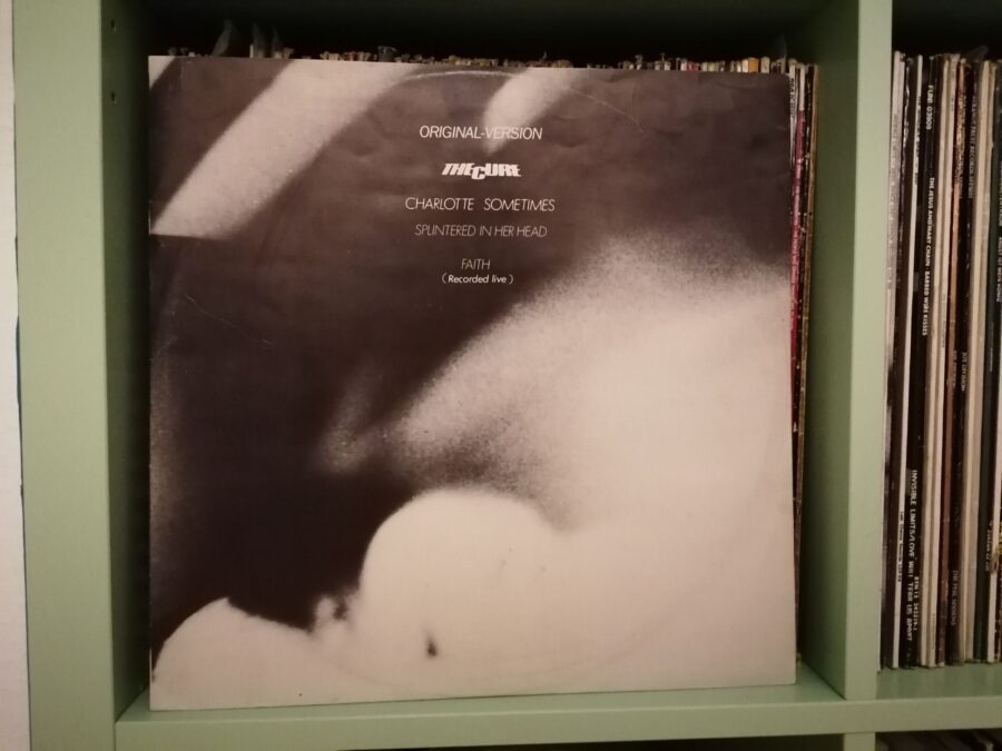 "Charlotte Sometimes" von The Cure. Maxi-Single steht im LP-Regal. Daneben sind weitere Schallplattenrücken zu sehen