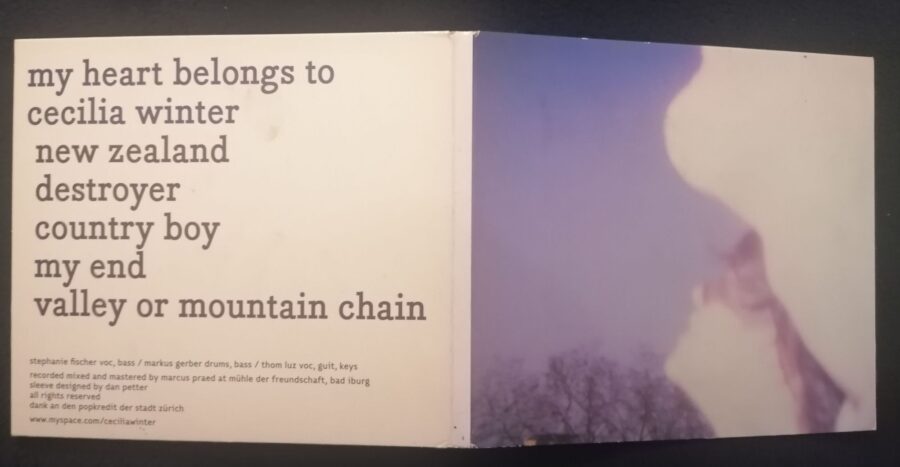 Aufgeklappter DigiPak von My Heart Belongs To Cecilia Winter. Links die Rückseite mit dem Bandnamen, der Trackliste sowie der Credits (in kleiner Schrift). Rechts das Cover-Foto, das ein Selfie zu sein scheint. Eine Person schaut in den blauen Himmel, das Foto ist unscharf. Es ist der Kopf und ein Teil des Armes zu sehen.